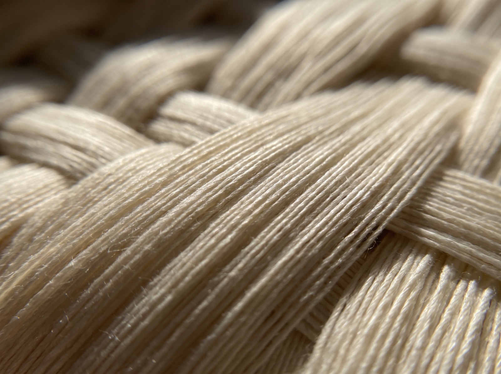Extreme macro of woven long-staple Egyptian cotton yarns showing the dense over-one under-three sateen weave structure and smooth fibers